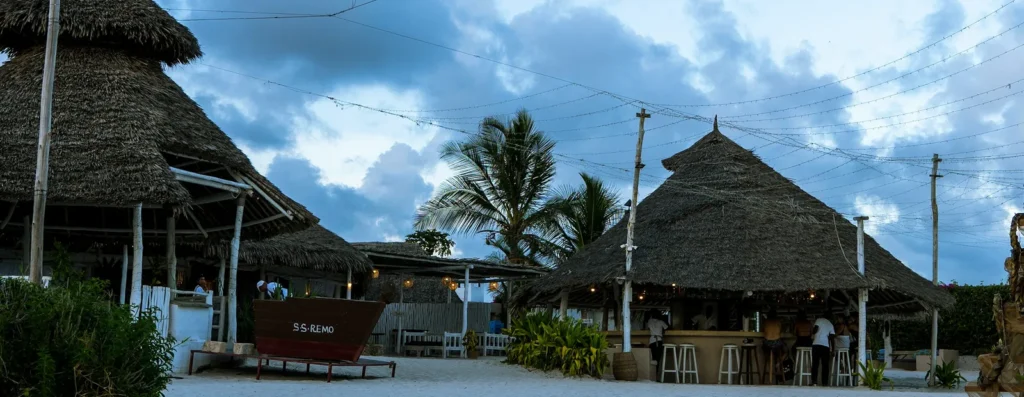 Thatched hotel buildings and a sandy guest area in Watamu, Kenya
